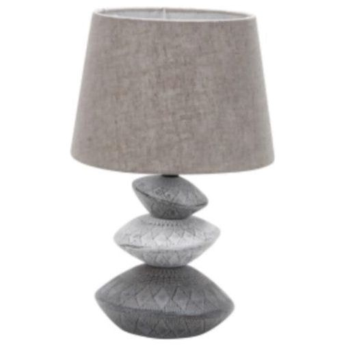 Grey table lamp with a textured fabric shade and a sculpted, stacked stone-like base